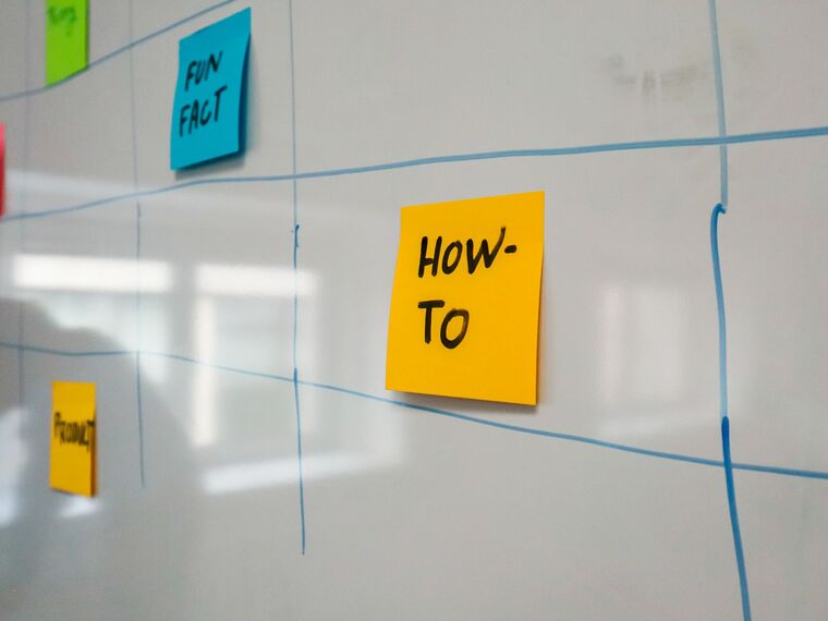 A whiteboard planning grid with colored sticky notes